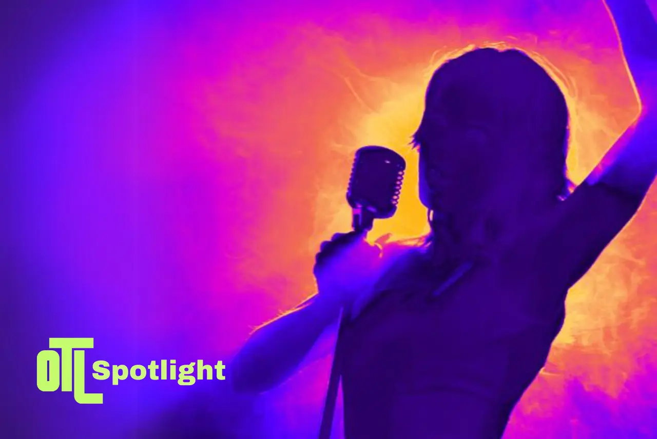 Silhouette of a performer singing into a microphone against a vibrant purple and blue background, with the OTL Spotlight logo in the foreground